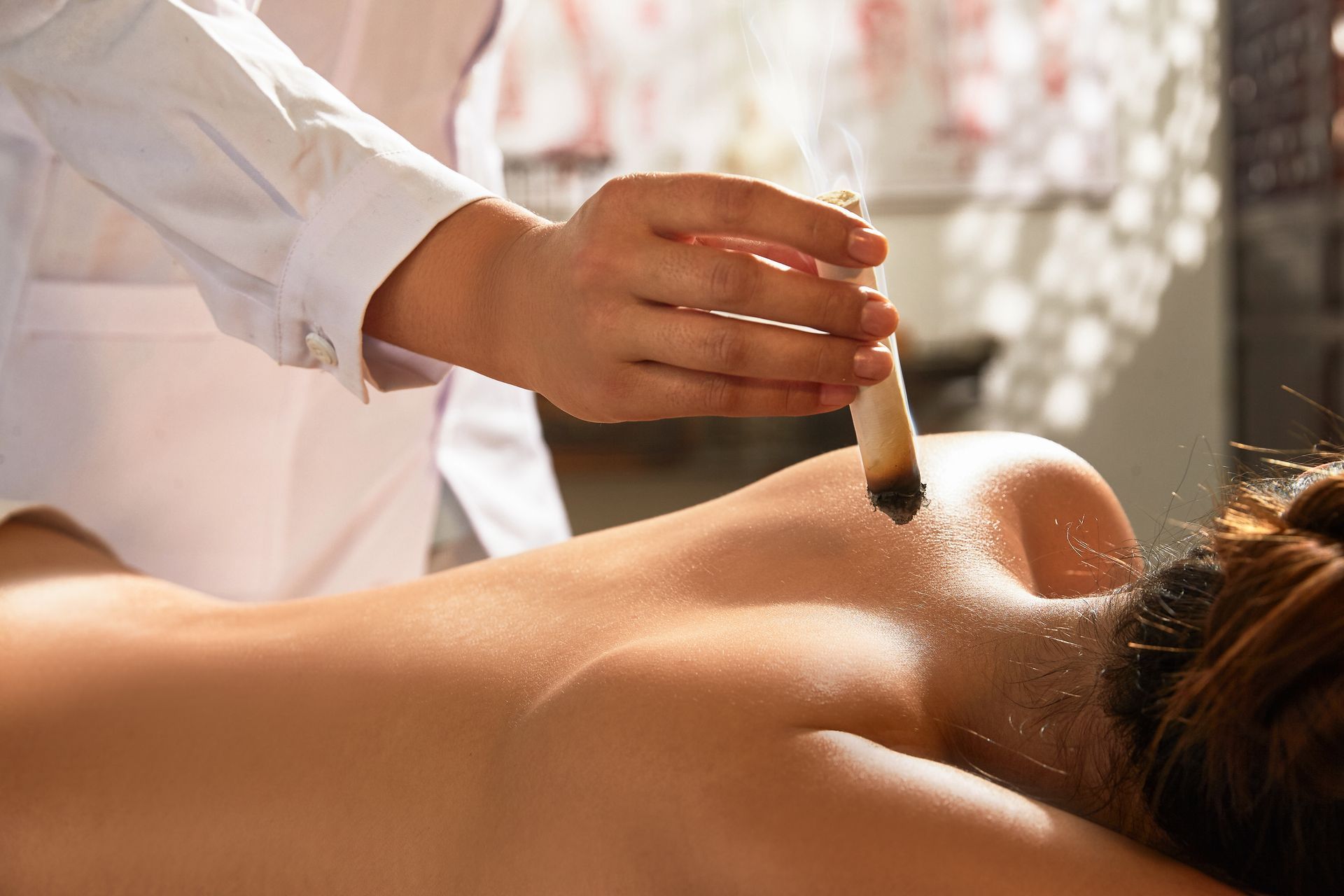 Una terapeuta de spa aplica aceite en la espalda desnuda de un cliente durante un masaje.